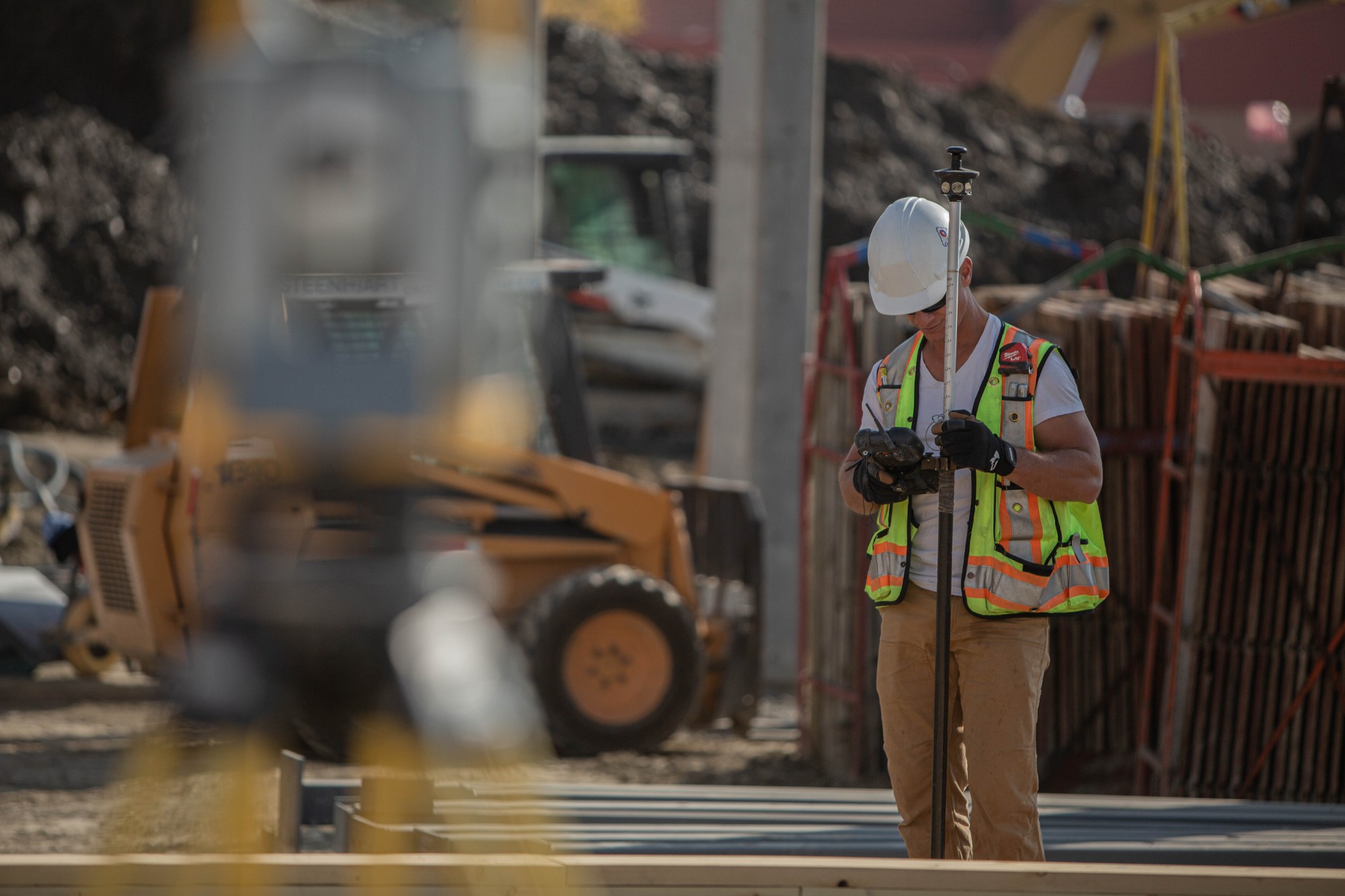Construction working using survey equipment on a project site