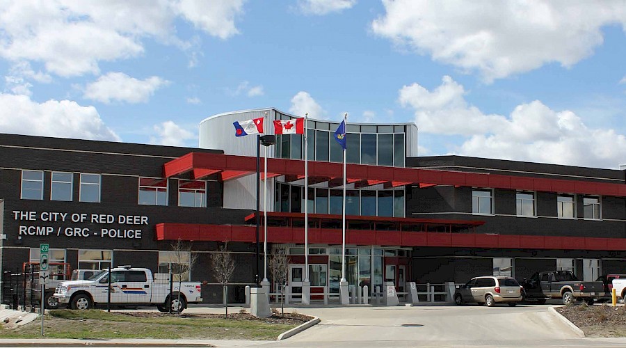 The exterior of the Red Deer RCMP station with flags waving in front of the entrance.