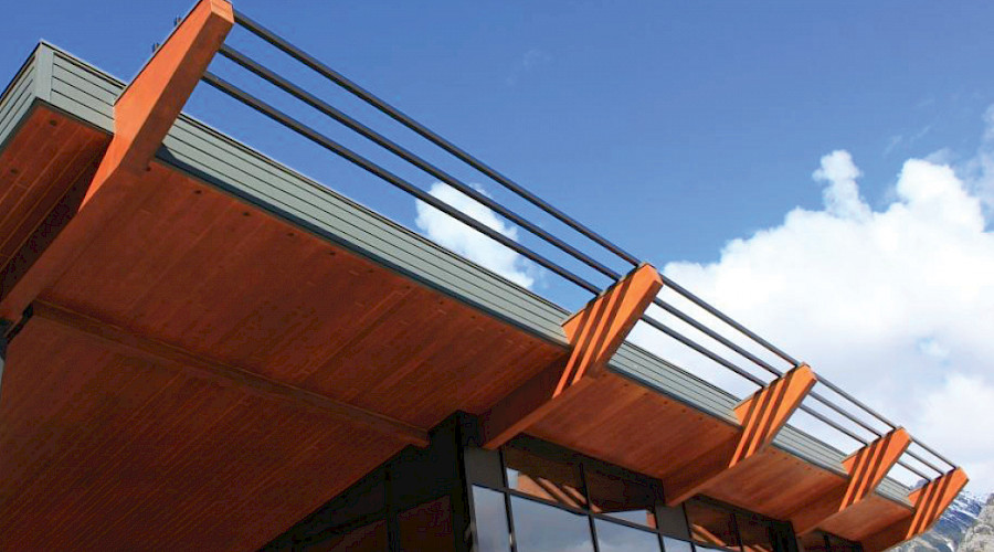 The mass timber roof of the Sulphur Slopes Visitors Pavilion under a blue sky.