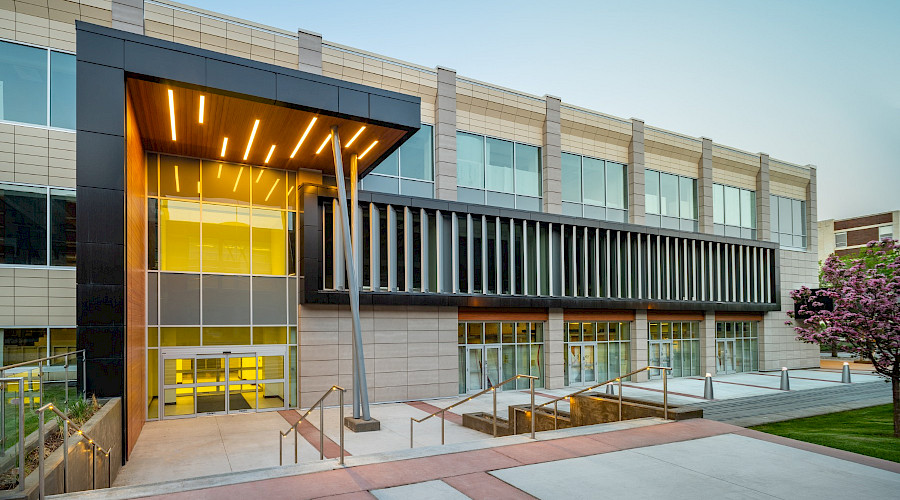 A photo of the exterior of the John Ware building in the evening, with the entrance lit up.