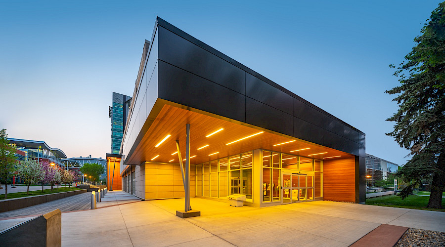 A photo of the corner exterior of the John Ware building at night with the entrance lit up.