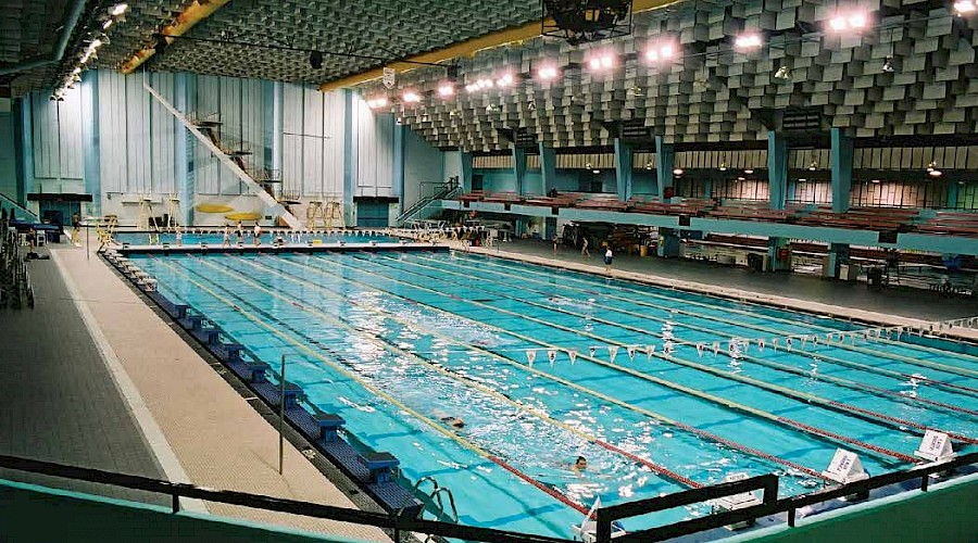 A large pool with multiple swimming lanes underneath bright lights.