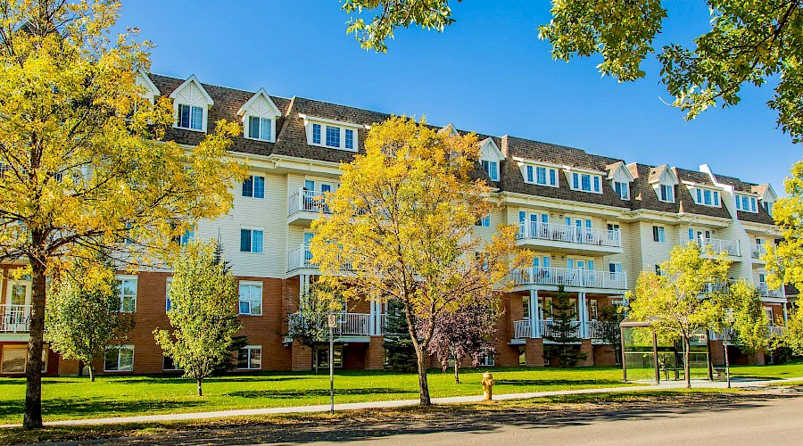 A photo of the white and brick exterior of the Rosedale Senior Centre behind trees.