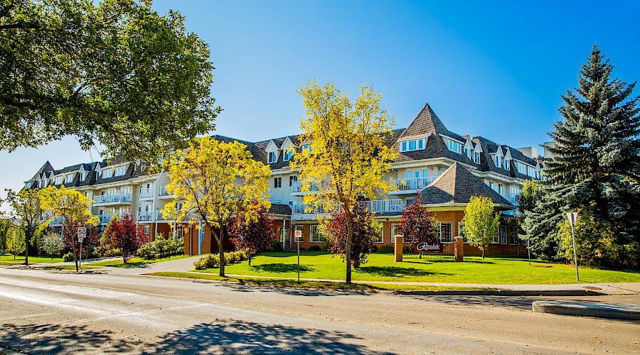 A photo of the white and brick exterior of the Rosedale Senior Centre behind trees.