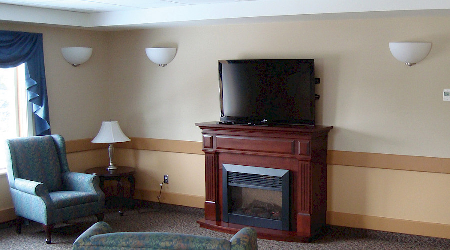 An electric fireplace in a room with two chairs.