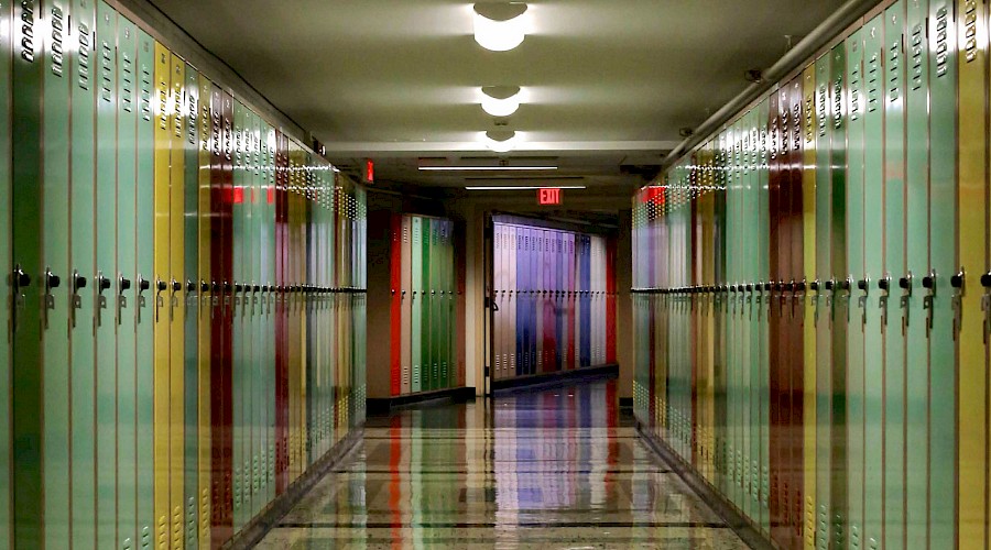 An empty hallway filled with multicoloured lockers.
