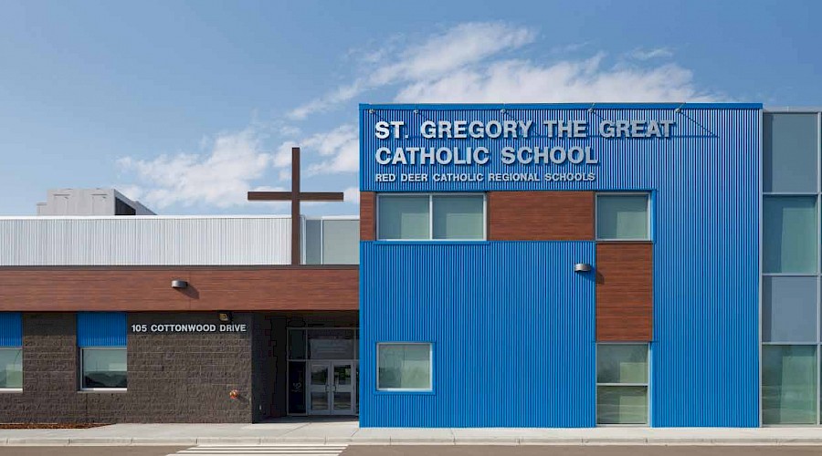 The blue exterior of St. Gregory the Great Catholic School, featuring it's wooden details and a large cross on the roof.