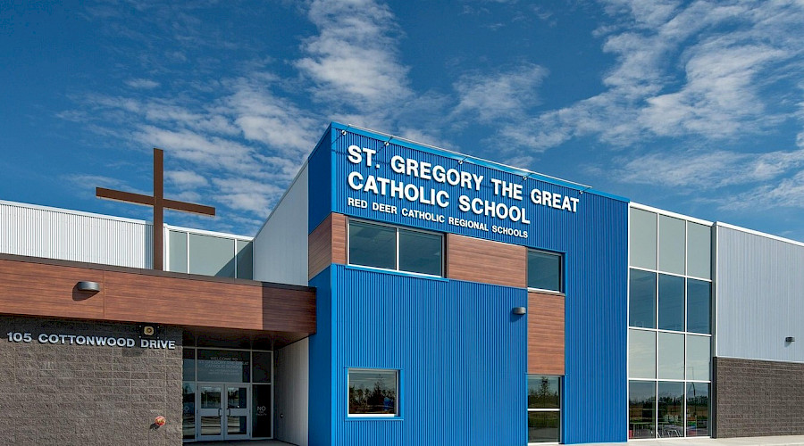 The blue exterior of St. Gregory the Great Catholic School, featuring it's wooden details and a large cross on the roof.