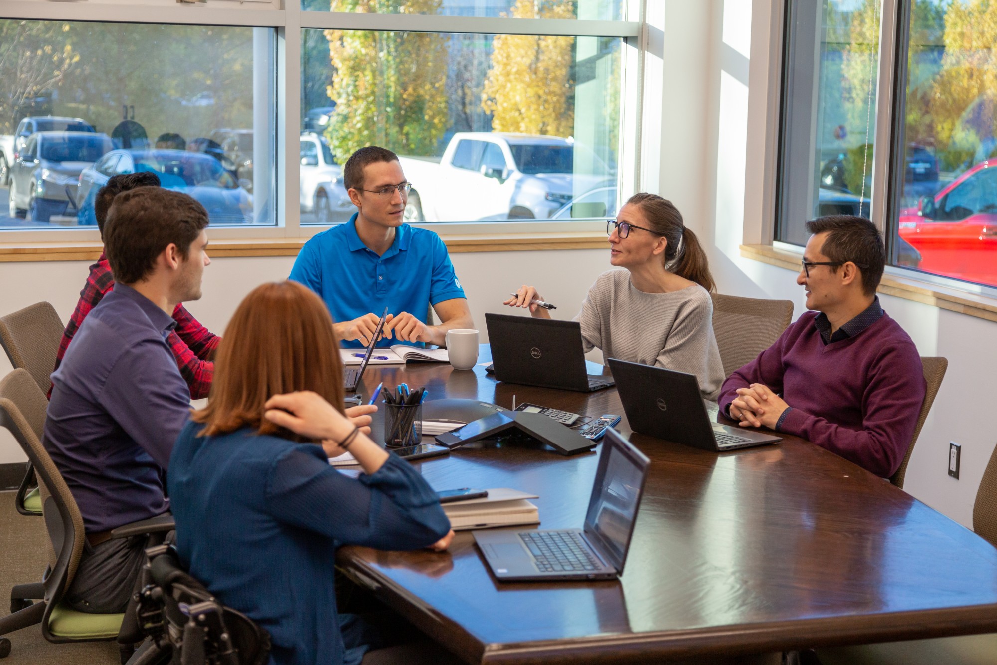 A group of Chandos employees sitting at a table in a bright meeting room discussing work.