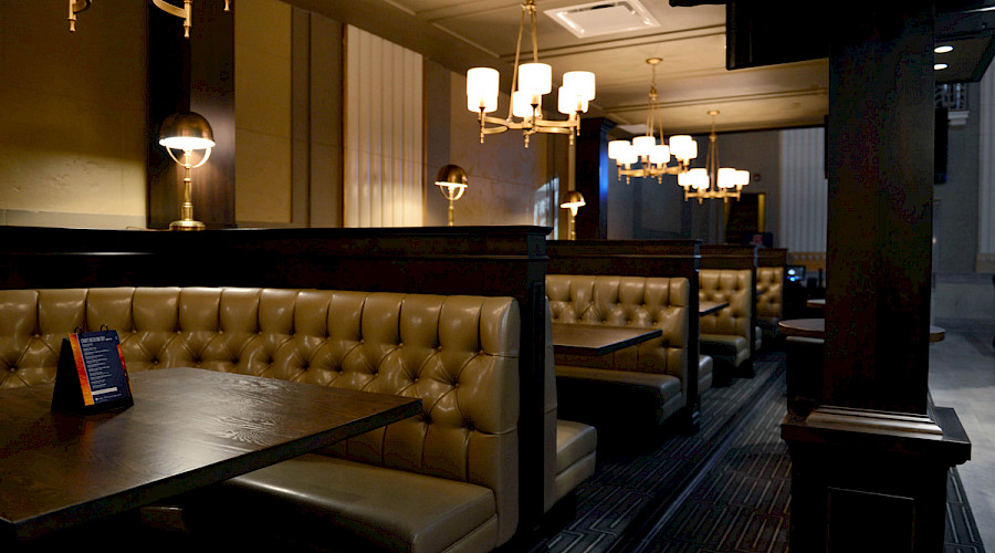 Rows of booths underneath chandeliers in a dim room.