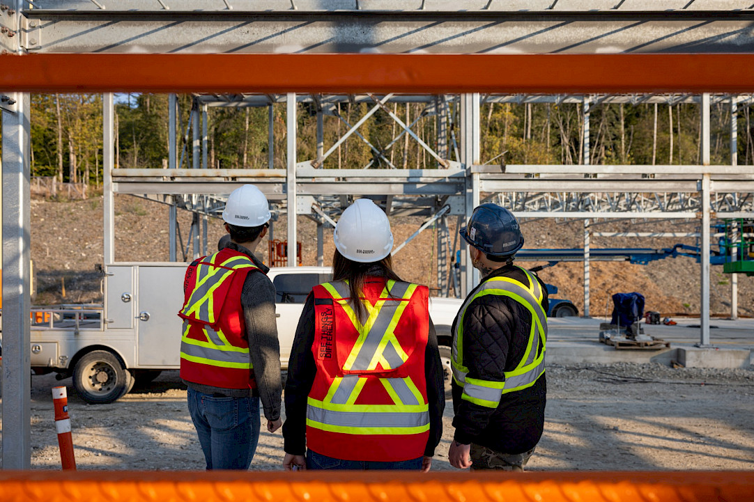 Three Chandos construction workers looking onto their site, wearing vests that read 