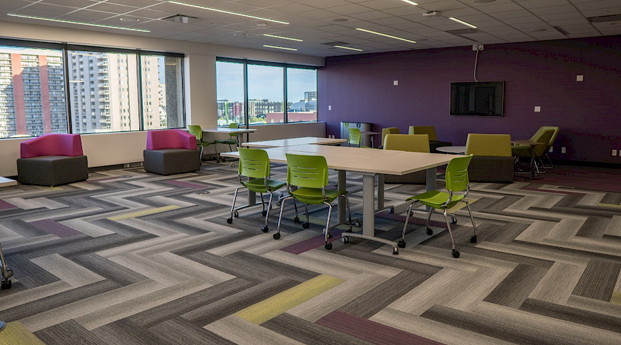 Groups of tables and chairs in a colourful common room.