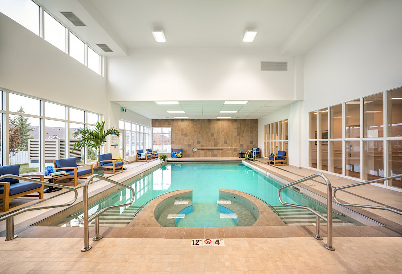 A bright blue indoor pool with sofas lining the walls.