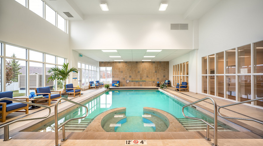 A bright blue indoor pool with sofas lining the walls.