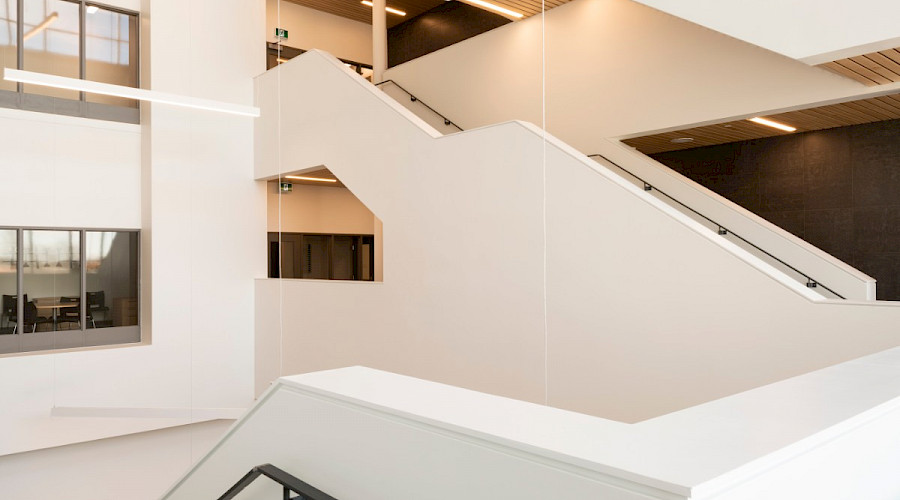 A large white staircase with long horizontal light fixtures hanging from the wooden ceilings.