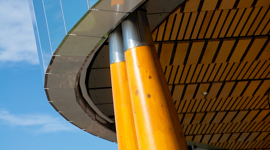 A photo of the rounded corner of the Blatchford District Energy System with it's mirror reflecting a bright blue sky.