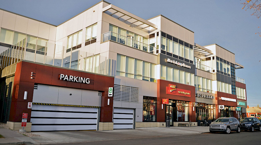 A parking garage next to stores in the Garrison Corner building along the street.