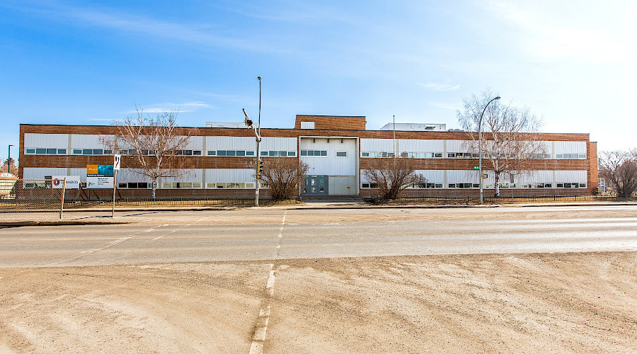 A road in front of the exterior of J.H. Picard school in front of a blue sky.