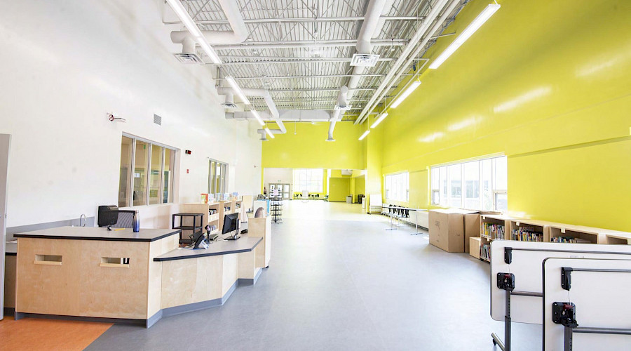 A large room with full bookshelves and desks against white and green walls.