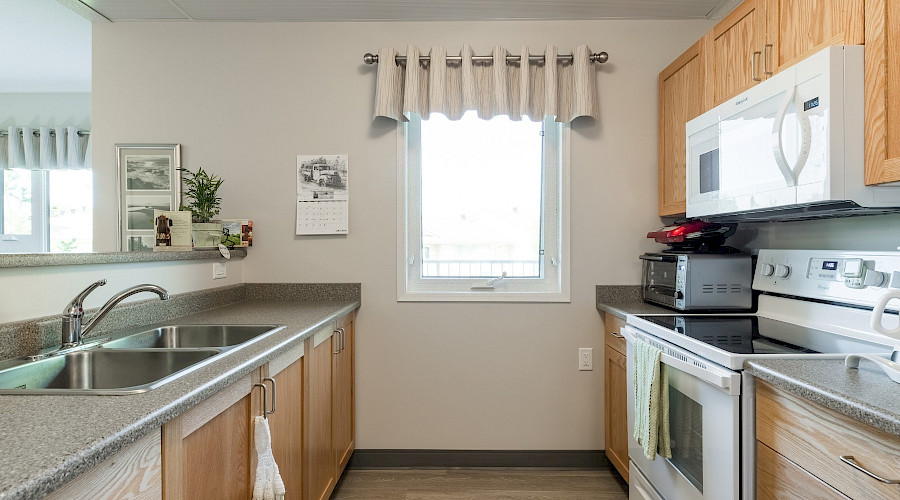 A kitchen with a bright window in the centre wall.