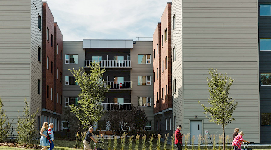 People walking in fronnt of the Sakaw Terrace buildings on a sunny day.