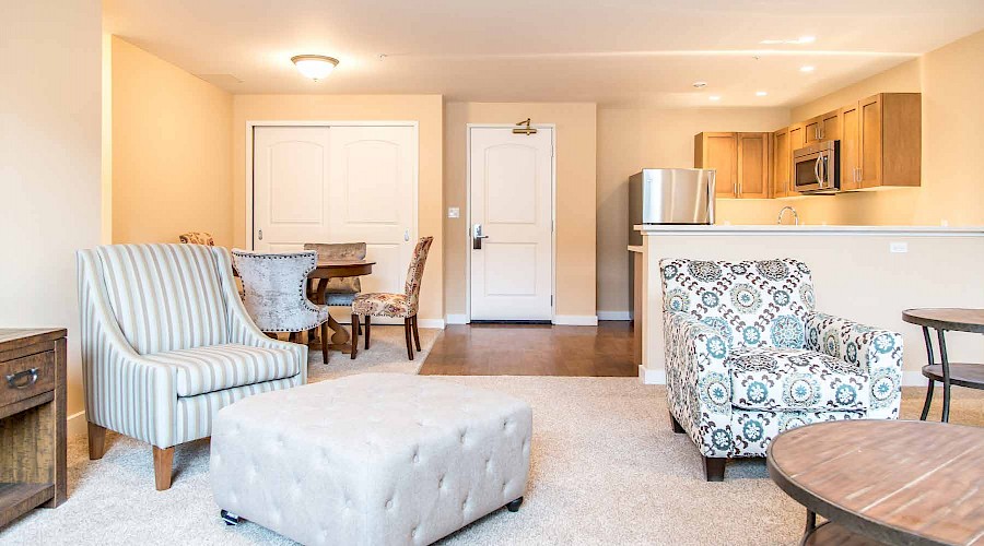 Lounge chairs in an apartment with a dining table and kitchen in the background.