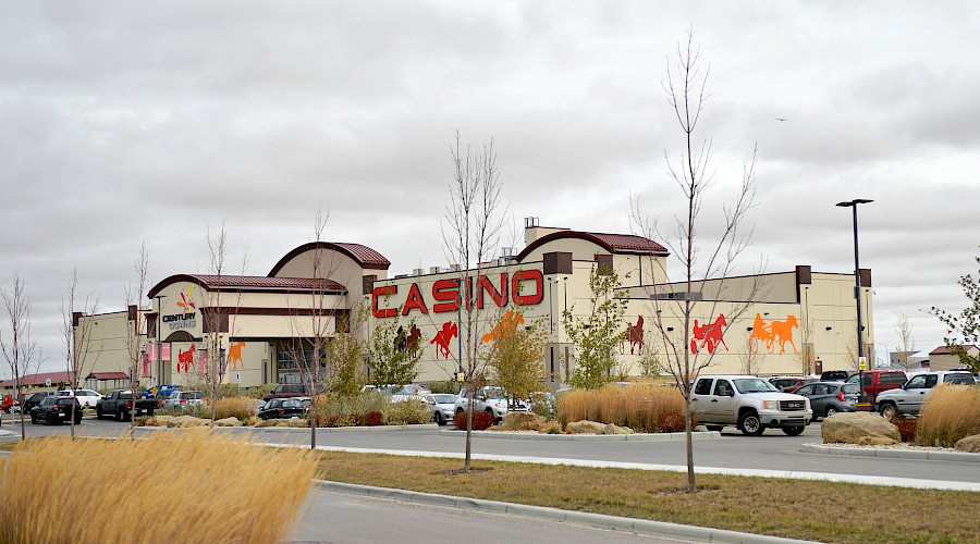 A photo of the Century Downs Casino showcasing it's exterior with images of horse racing and large, bright red letters that read 