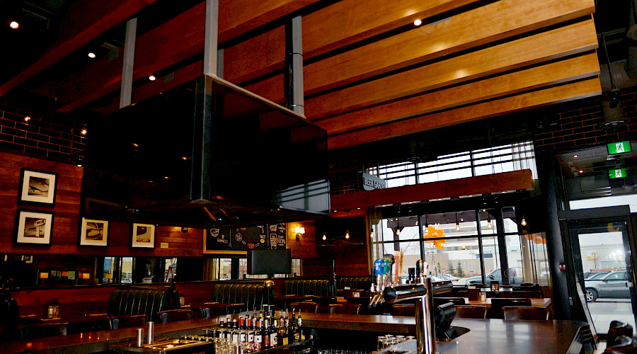 A large TV hung in the centre of a restaurant surrounded by a bar top.