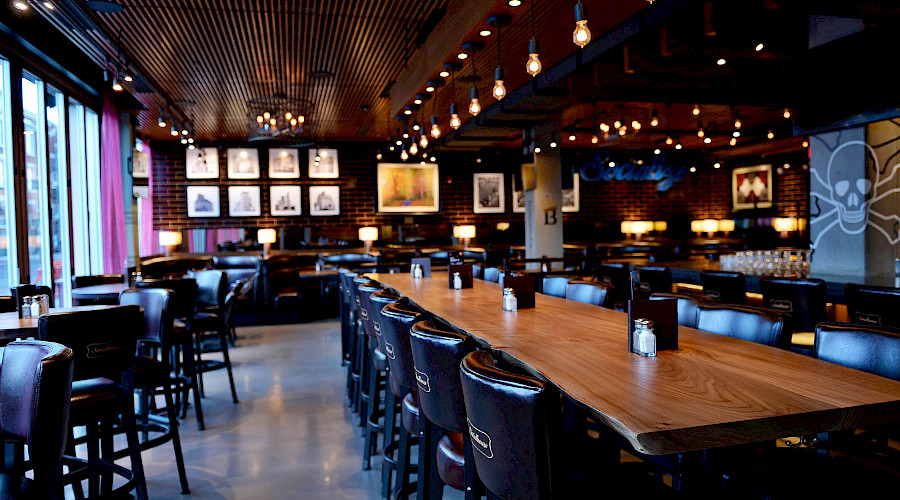 Single lightbulbs hanging above a long table with rows of chairs in a restaurant.