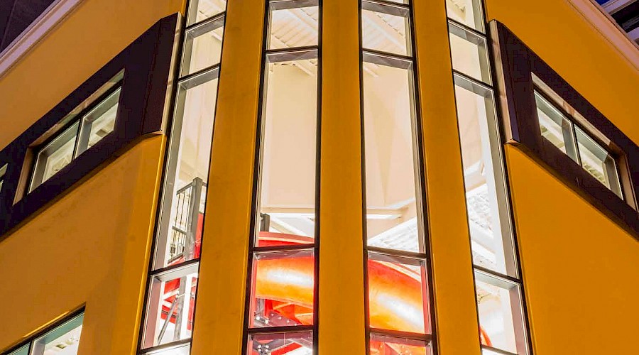 A photo of a large slide seen through the outdoor windows of a hotel.