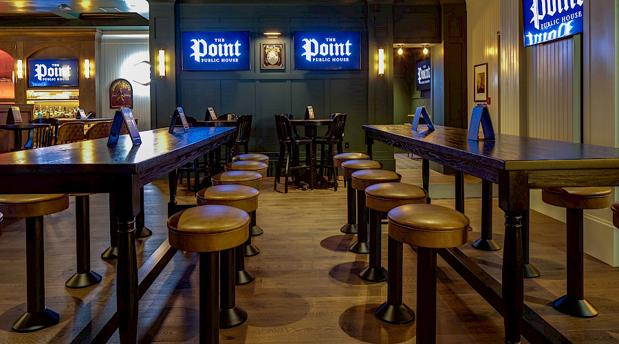 Two long tables lined with stools with TVs on the walls in the background that read 