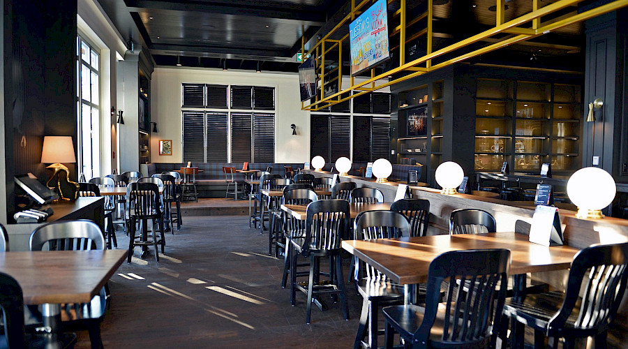 Dining tables and chairs in a bright restaurant with sun shining through the windows.