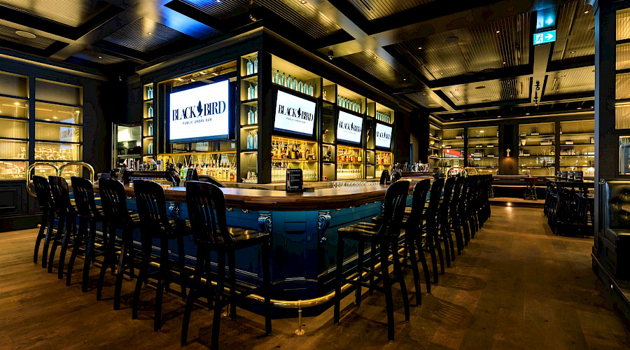 A large bar with rows of chairs in the centre of a restaurant room.