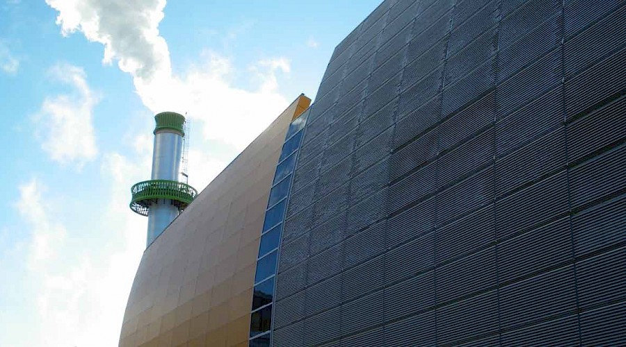 The cooling plant releasing steam behind a curved wall.