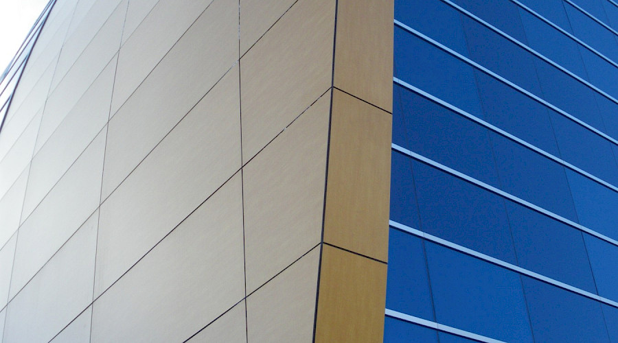 The corner of a curved wall on a building, where glass windows and wood paneling meet.