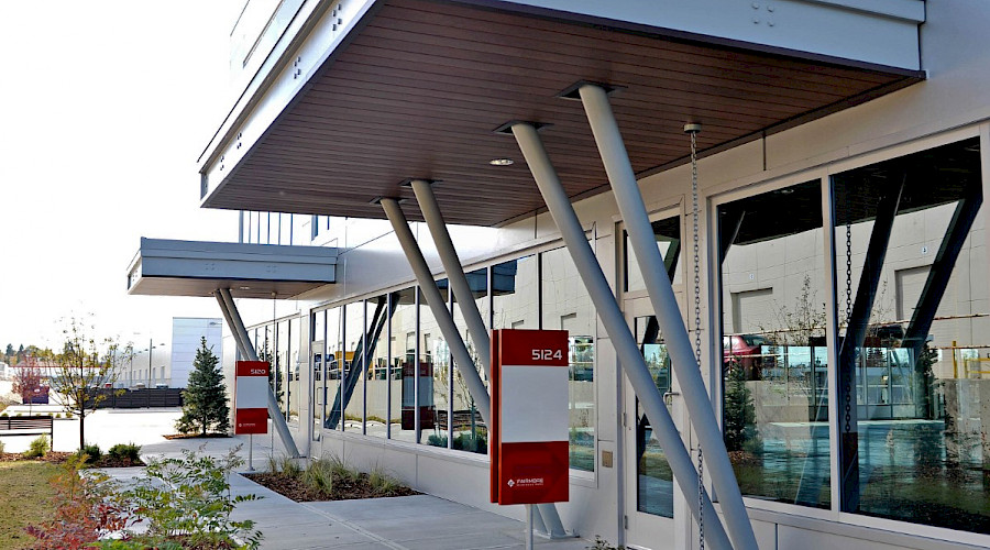 A walkway in front of a building with multiple windows and entrances.