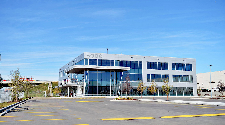 A parking lot in front of a building with multiple windows and '5000' in signage on the top of the building.