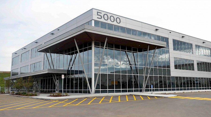 A parking lot in front of a building with multiple windows and '5000' in signage on the top of the building.