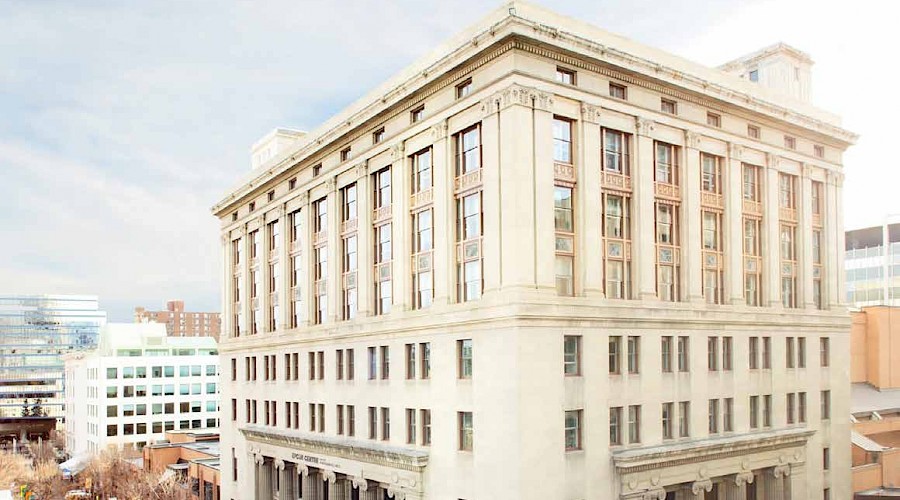 A corner shot of the cream exterior of a large building with antique detailing.