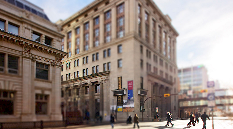 A photo of people walking across the street in front of the Calgary Public Building.