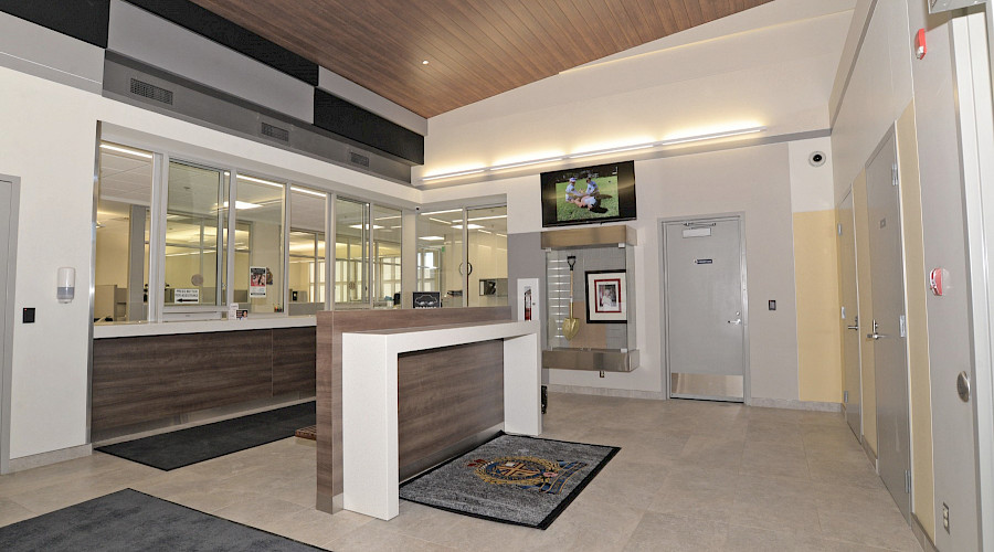 The reception area in the Lacombe Police Facility, with desks behind glass windows.