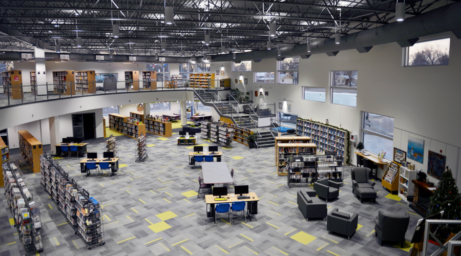 The view from the second floor of a large library, looking onto rows of bookshelves and tables.