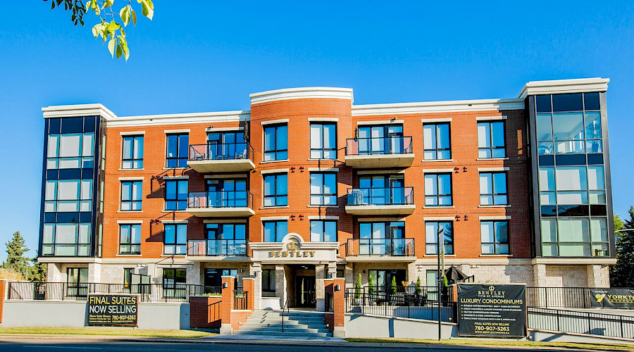 A photo of the front of the Bentley Condominiums building with a clear blue sky in the background.