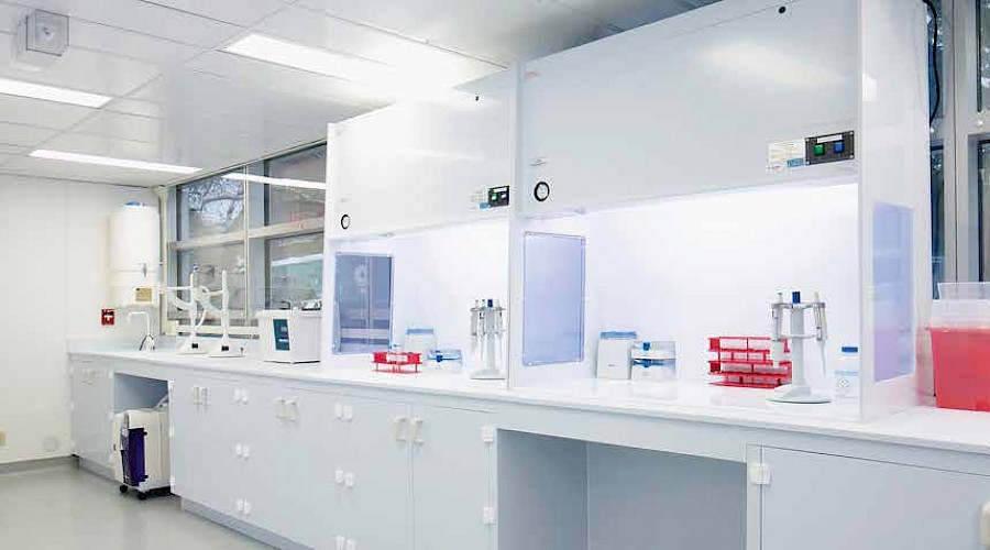 Laboratory equipment on countertops lining the bright white walls inside a laboratory room.