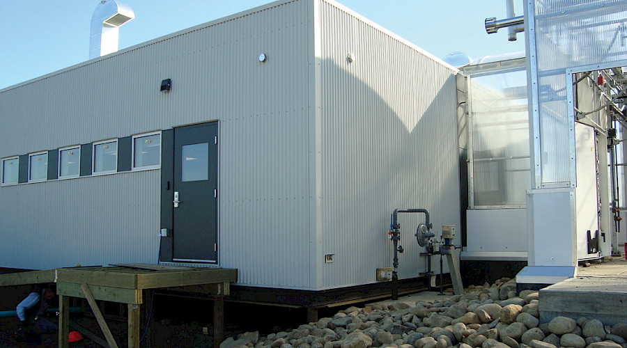 A large white shed with a grey door and windows.