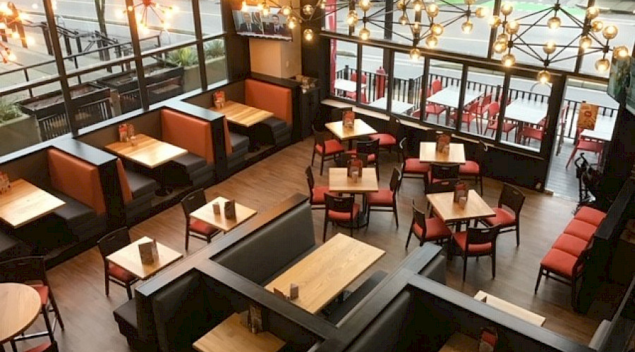 A shot from above of booths and tables underneath large light fixtures in a restaurant.