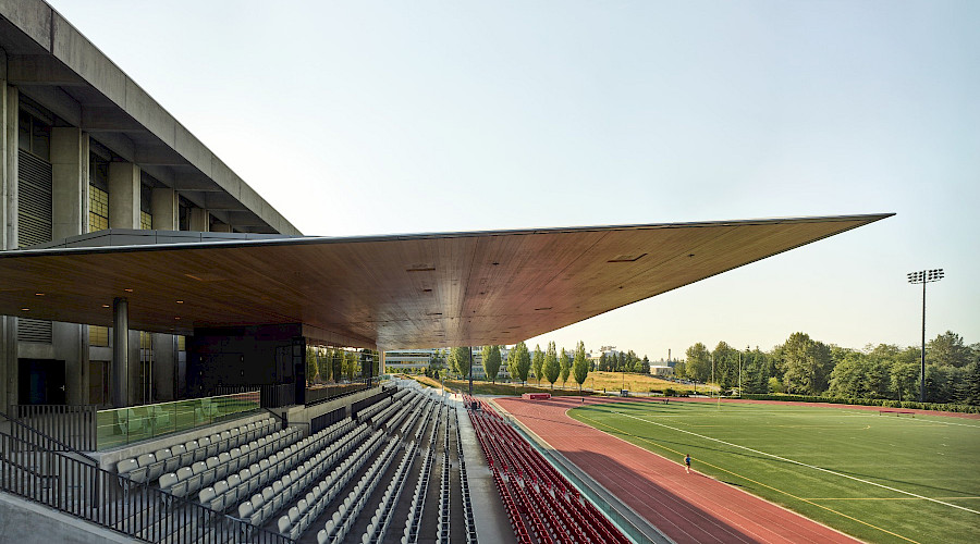 A photo of the Simon Fraser University stadium with the sun reflecting off the mass timber roof.