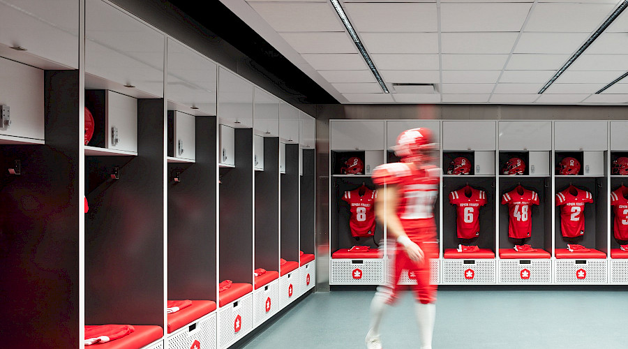 A football player dressed in gear in the Simon Fraser University locker room.