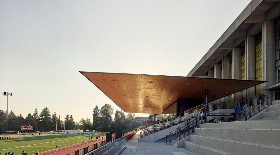 A photo of the Simon Fraser University stadium with the sun reflecting off the mass timber roof.