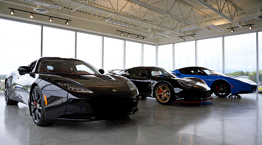 Three Lamborghinis on display in a room with large floor to ceiling windows.